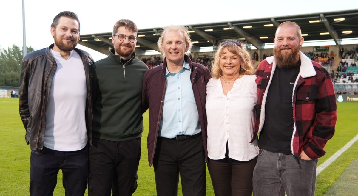 Liam Buckley with four family members, standing together on the pitch at Tallaght Stadium in front of a full stand.